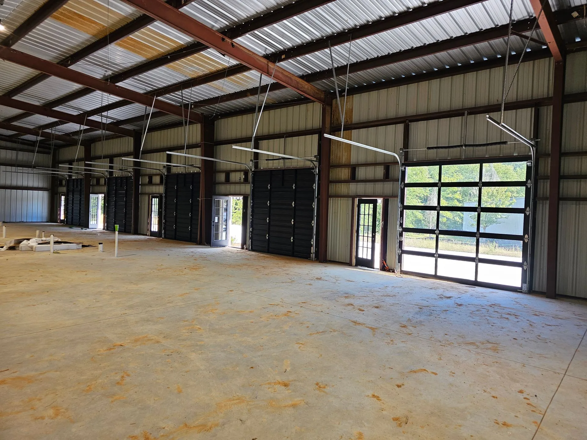 A large empty warehouse with a lot of doors and a concrete floor.
