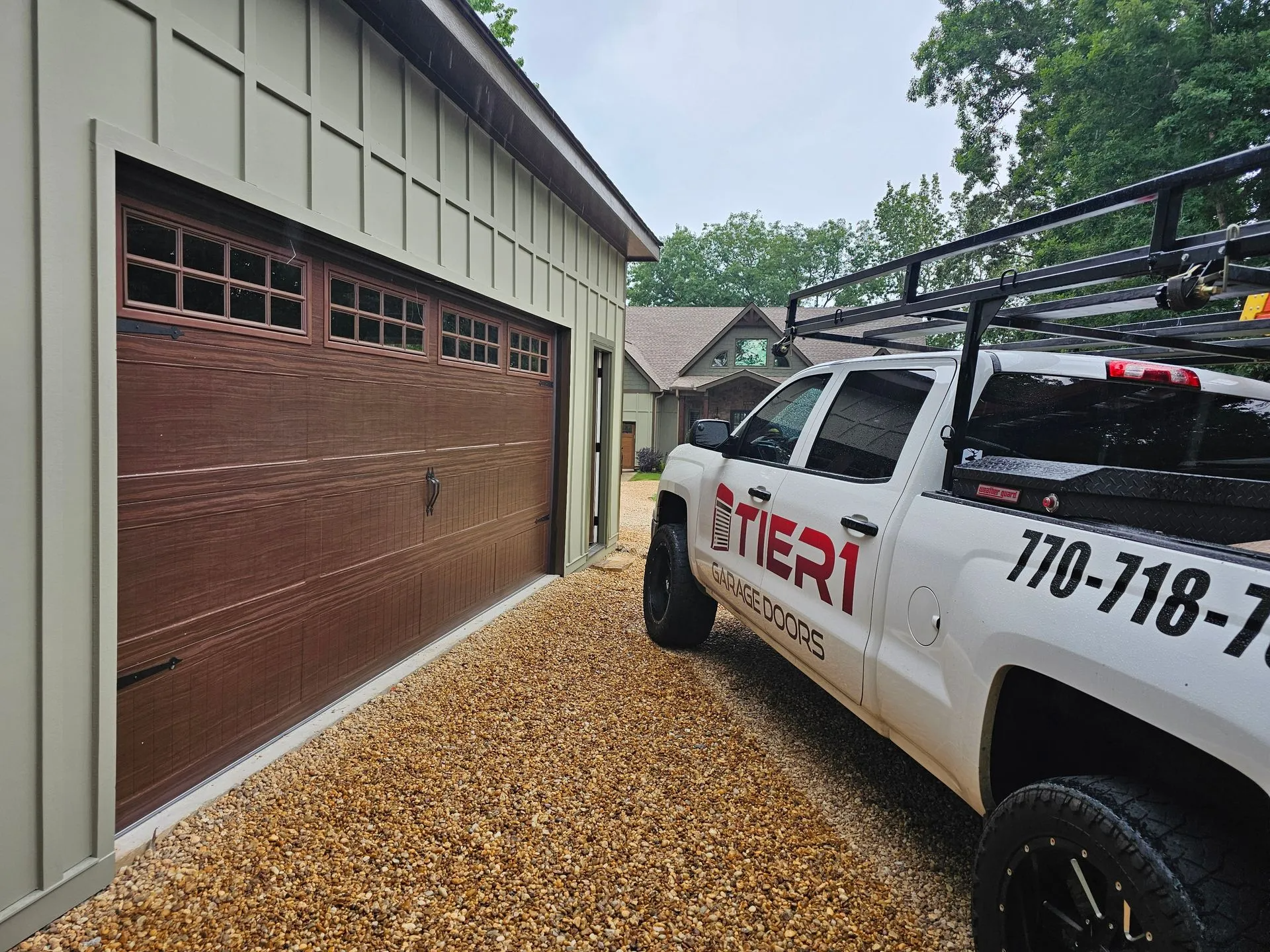 A white truck is parked in front of a garage door.