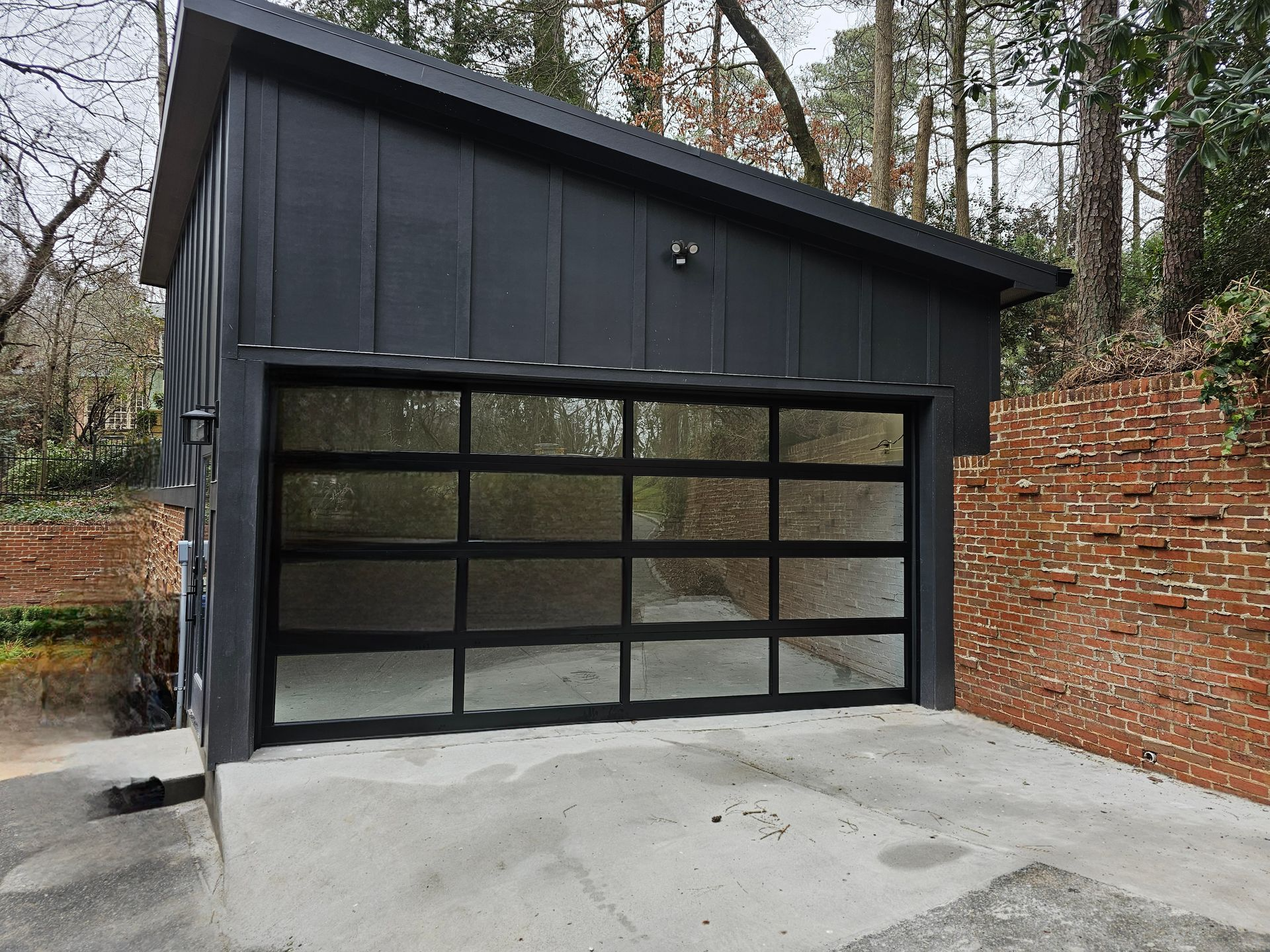 A black garage with a glass door and a brick wall