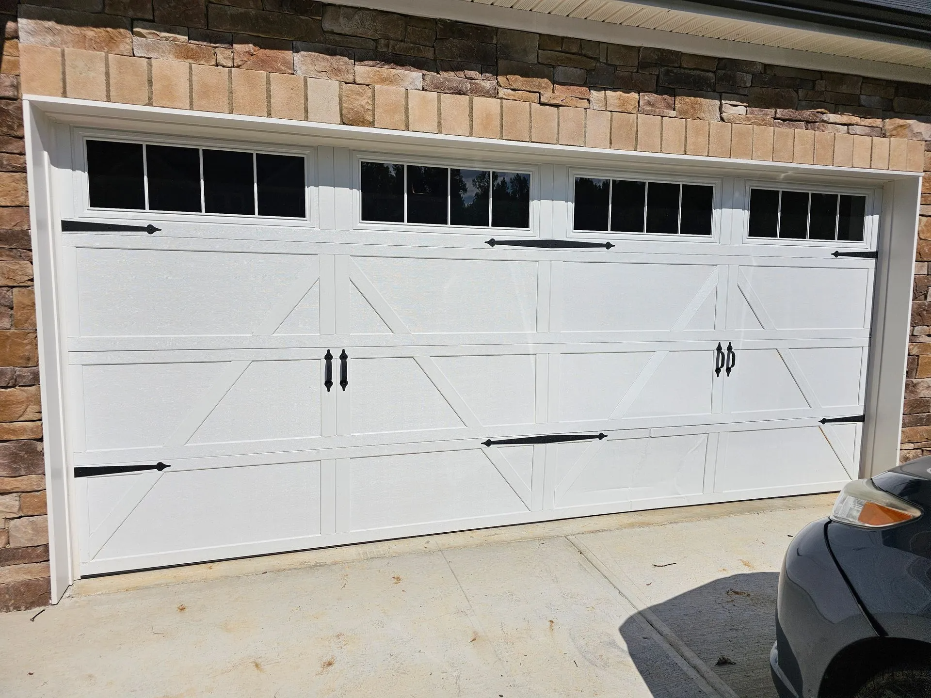 A car is parked in front of a white garage door.
