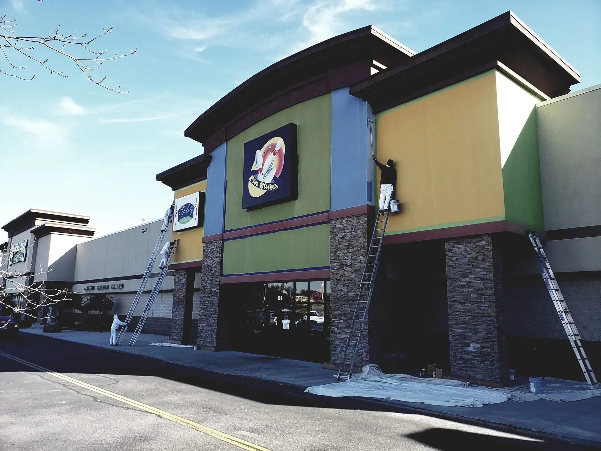 Factory interior with blue machinery, yellow support beams, and overhead lighting.