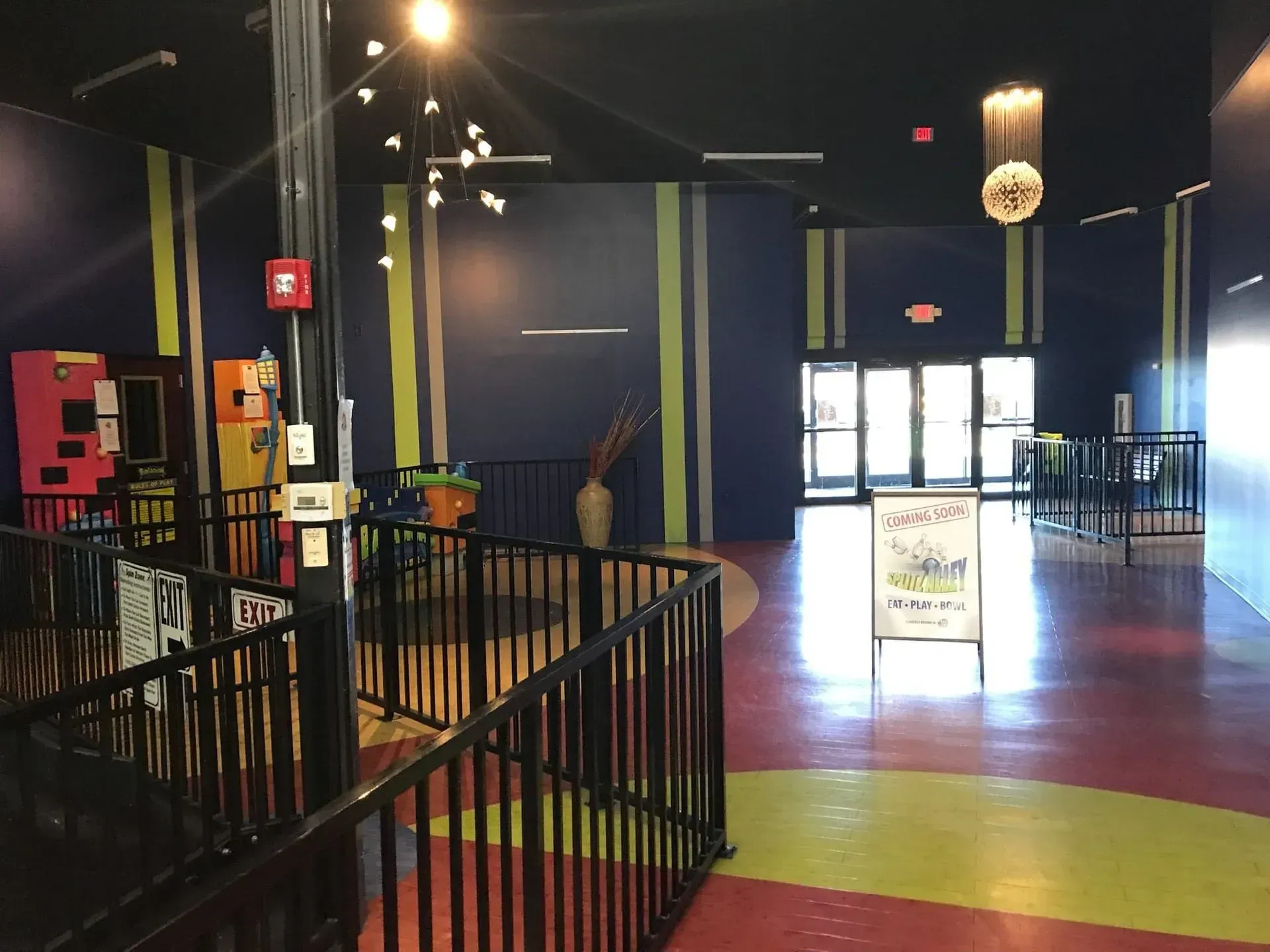 Interior of an arcade with colorful walls, a staircase, and arcade games.