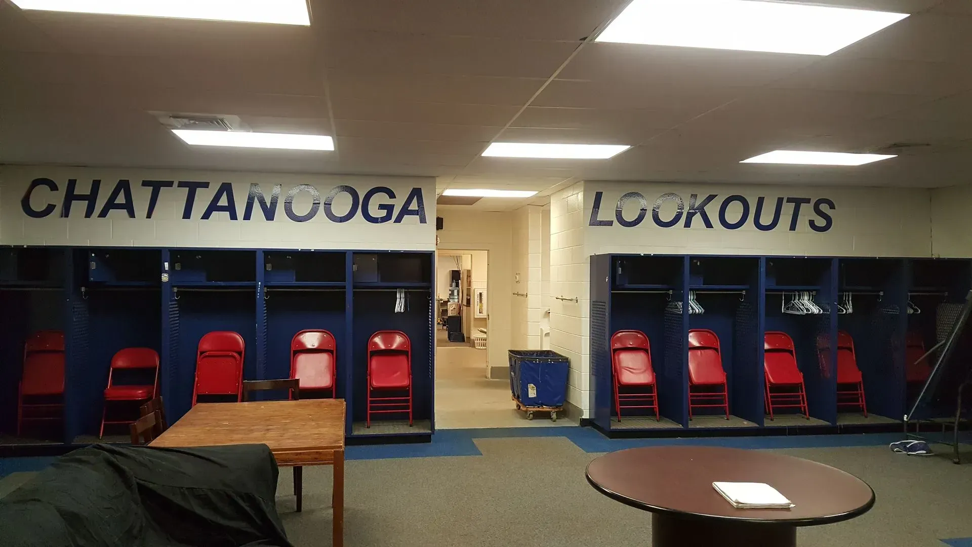 Chattanooga Lookouts baseball team locker room with blue lockers, red chairs, and team name on the wall.