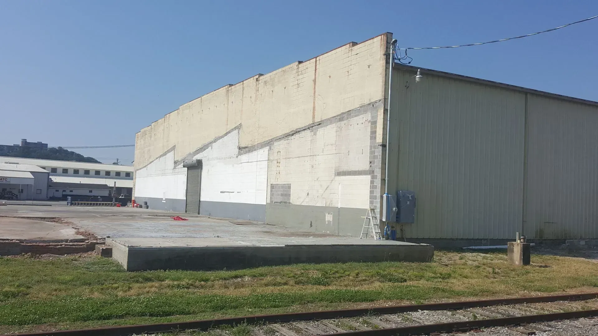 A yellow industrial building next to railroad tracks under a blue sky.