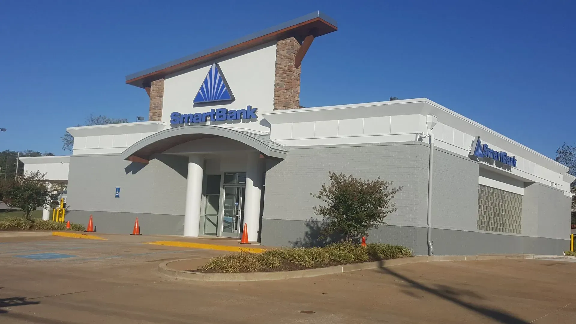 Exterior of SmartBank building with blue triangular logo on a sunny day.