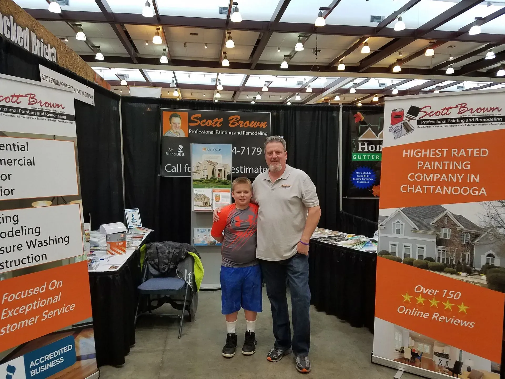 A man and a boy pose at a booth with 