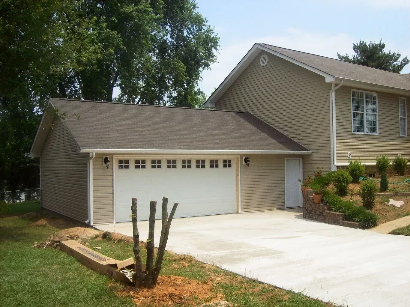 Beige house with attached garage and concrete driveway on a sunny day.
