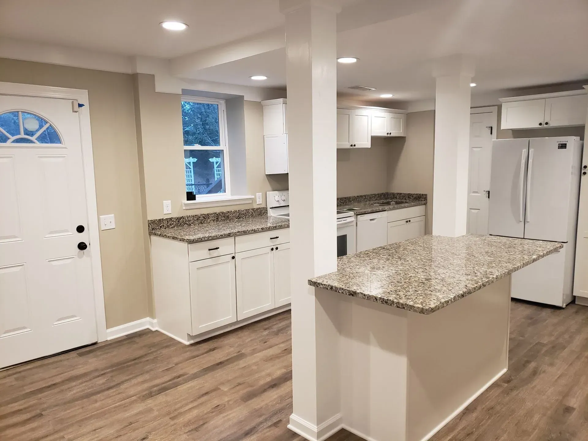 Newly renovated kitchen with white cabinets, granite countertops, and an island.