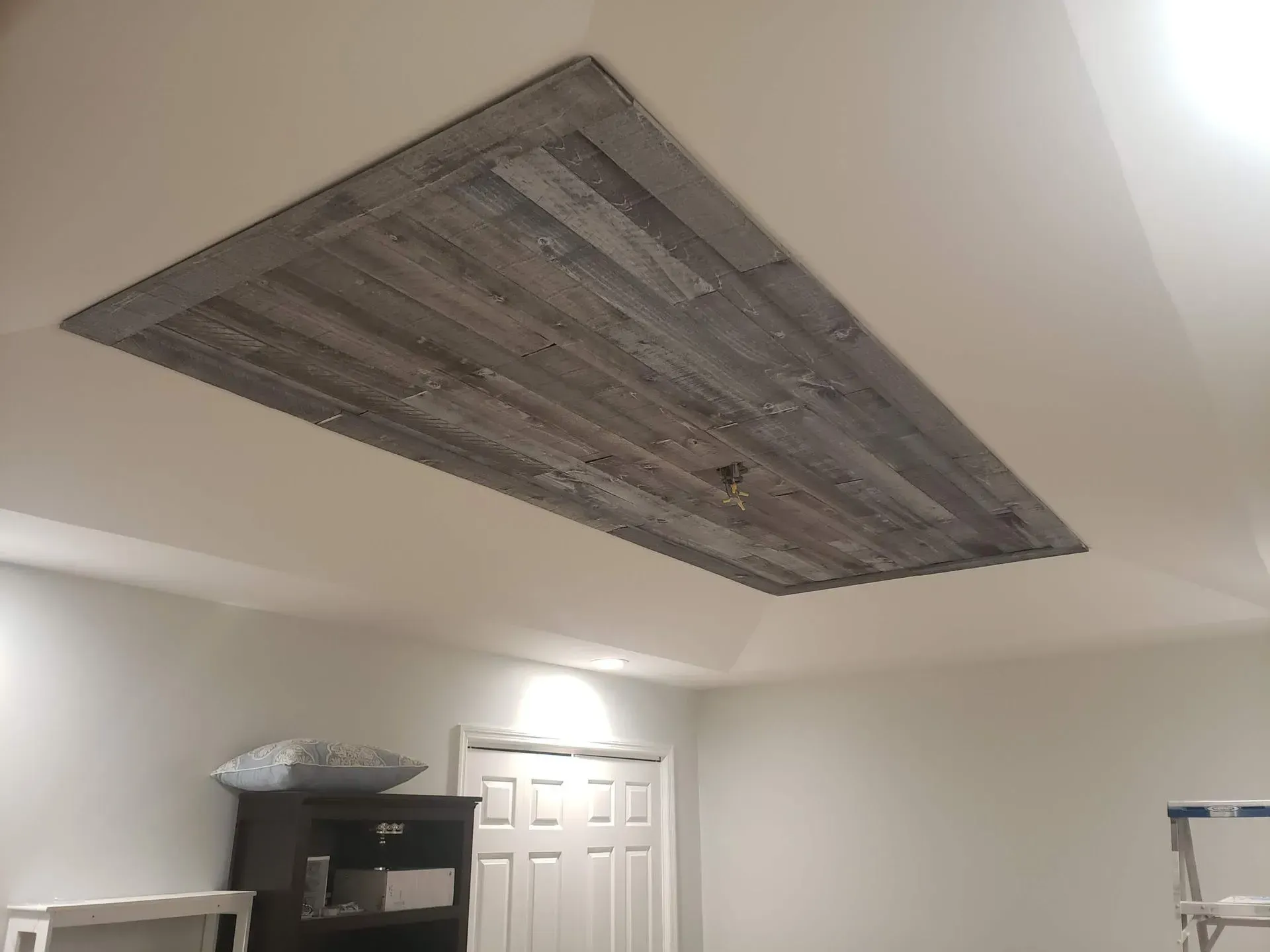 Wooden plank ceiling insert in a white room.