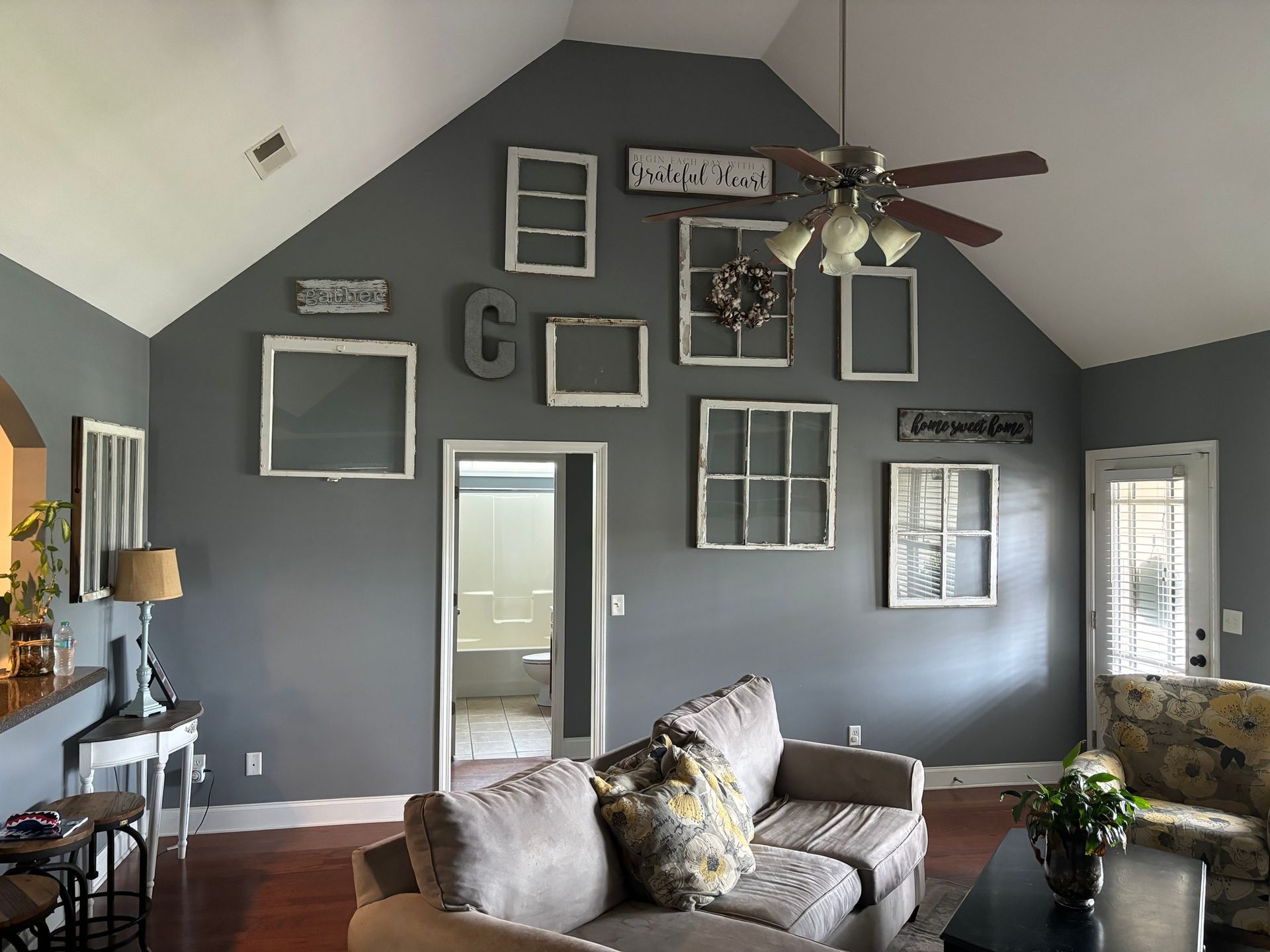 Gray living room with wall art of various old window frames; sofa in the foreground.