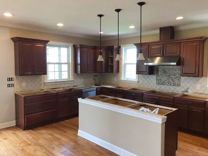 Kitchen undergoing renovation with dark wood cabinets, island, and light countertops.