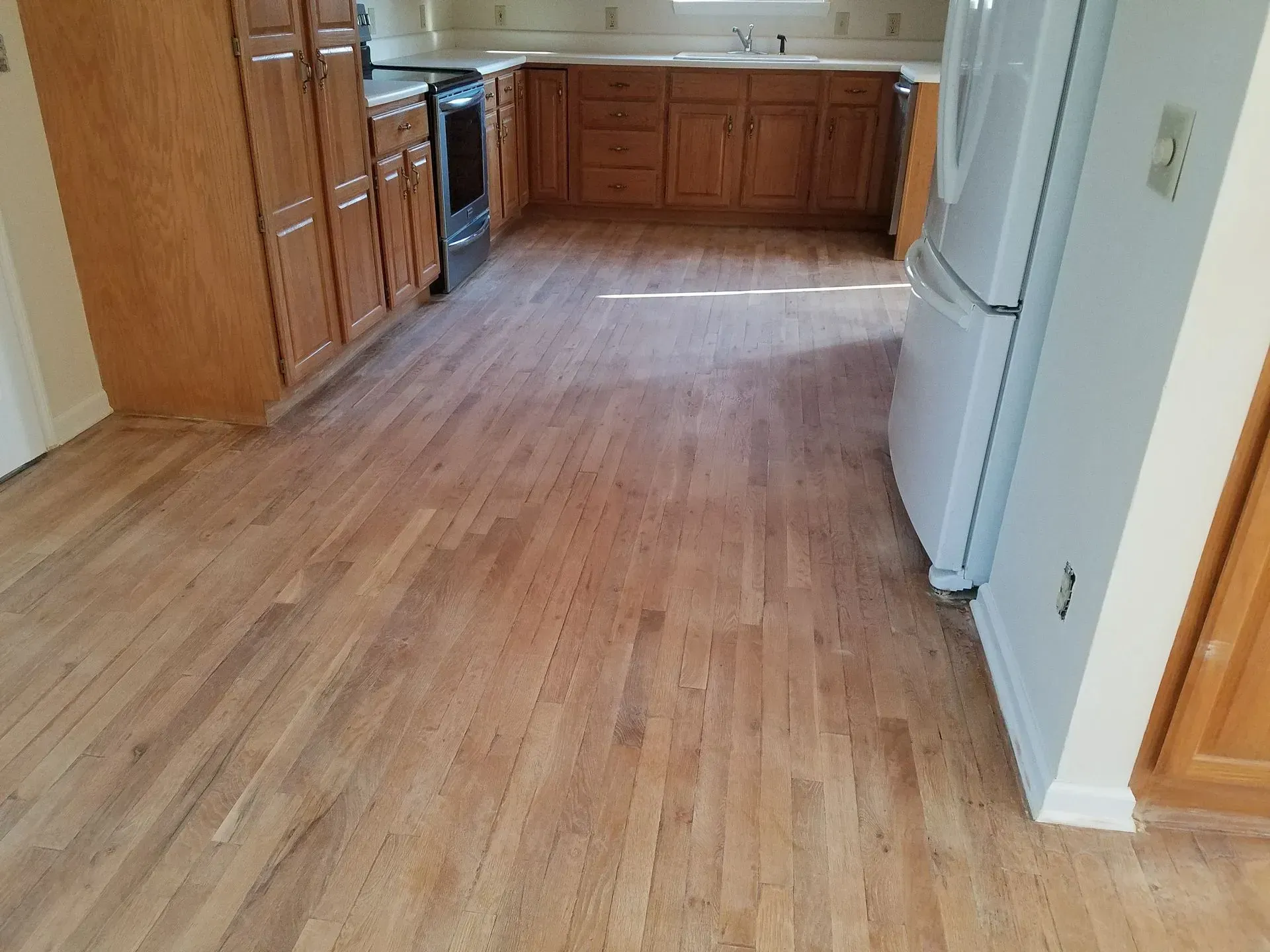 Kitchen with light wood floors, cabinets, and white appliances.