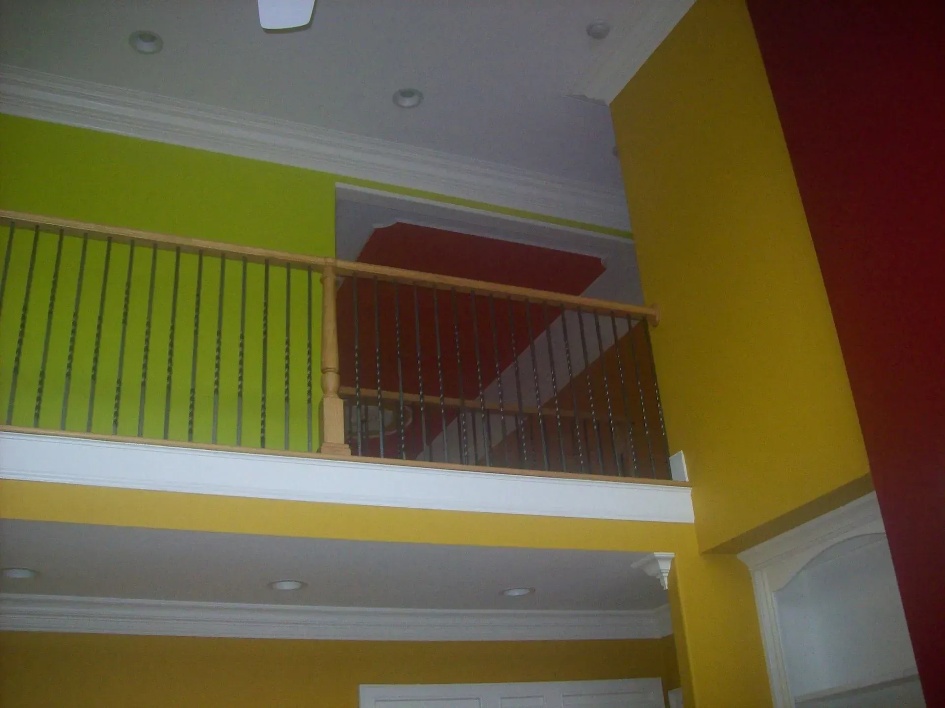 Interior with a yellow, green, and red color scheme, a balcony, and a high ceiling.