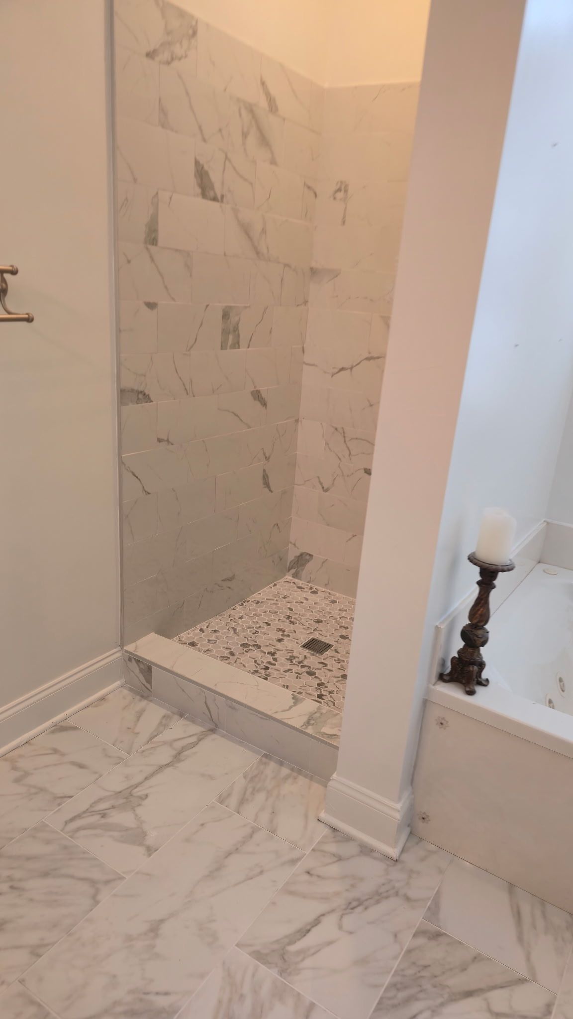 Marble-tiled bathroom shower alcove with unfinished floor and white walls