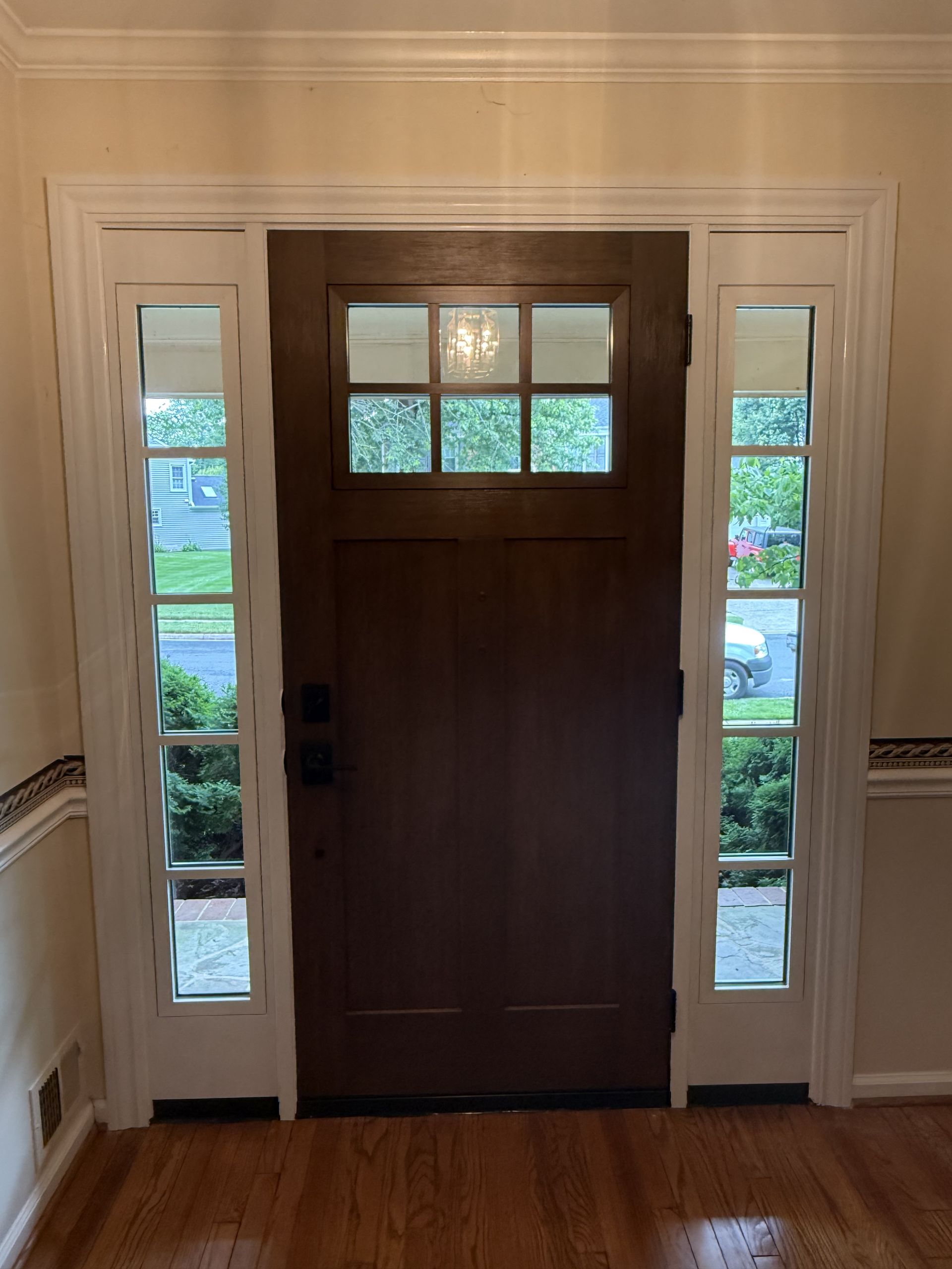Dark brown front door with sidelights and white trim.