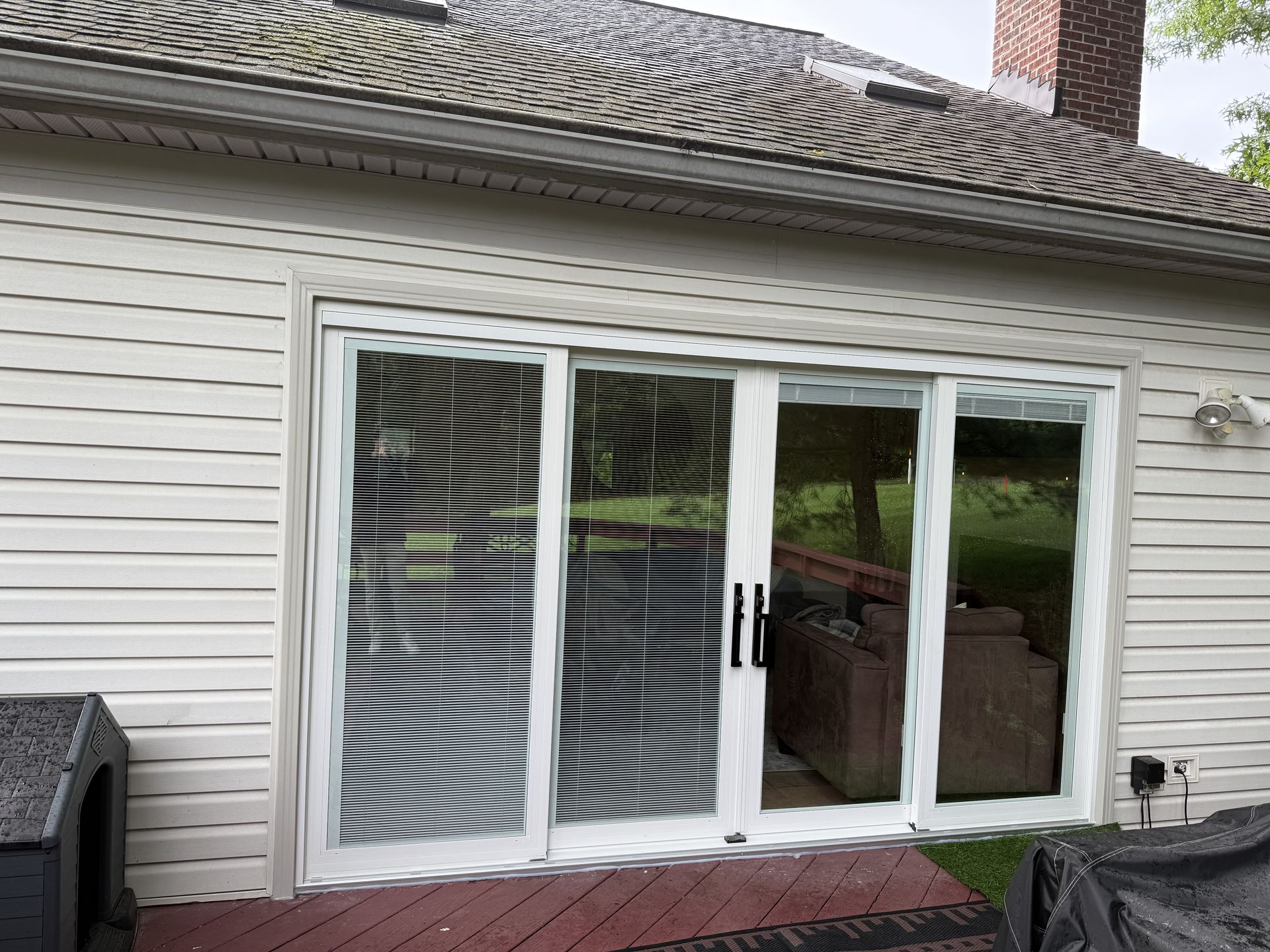 White sliding glass doors on a beige house, with a reflection distorting the view inside.