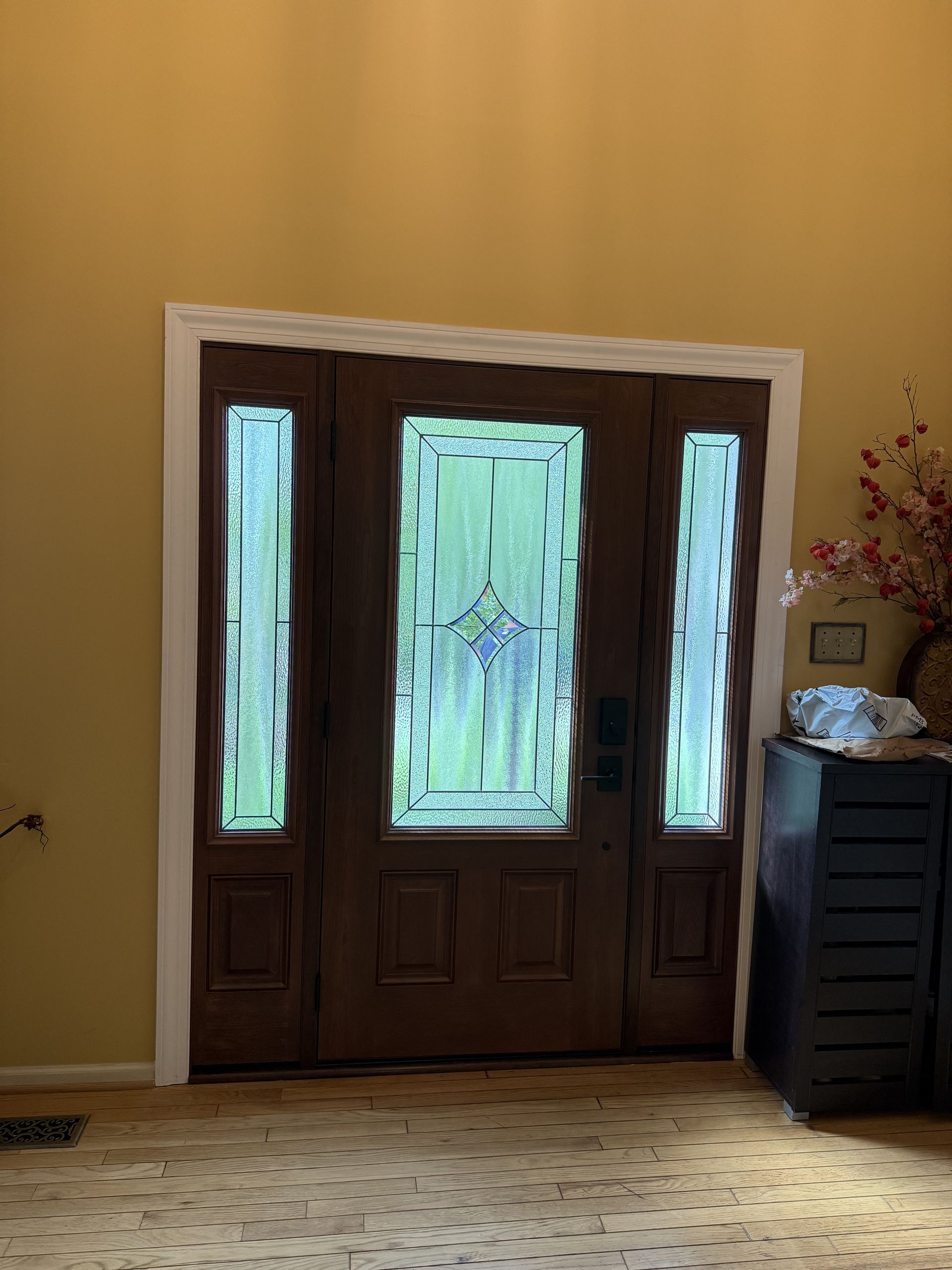Brown double doors with glass panels in a yellow-walled entryway.