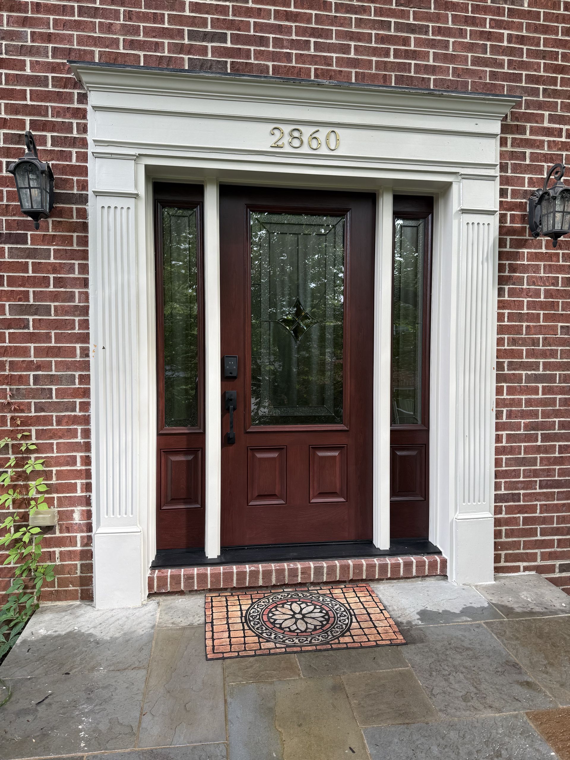 Red brick house with a brown door, sidelights, white trim, and house number 2660.