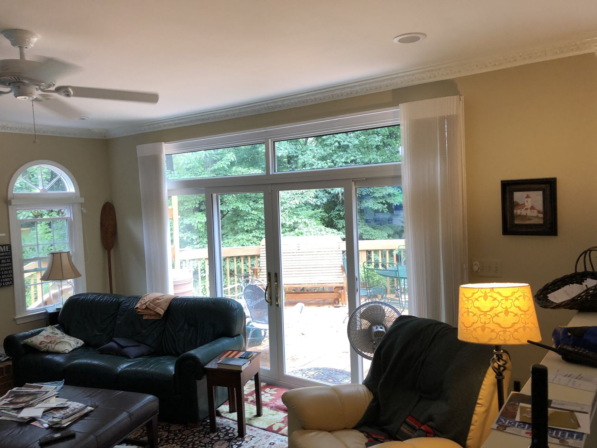 Living room with large sliding glass doors to a deck, green couch, chair, and tan walls.