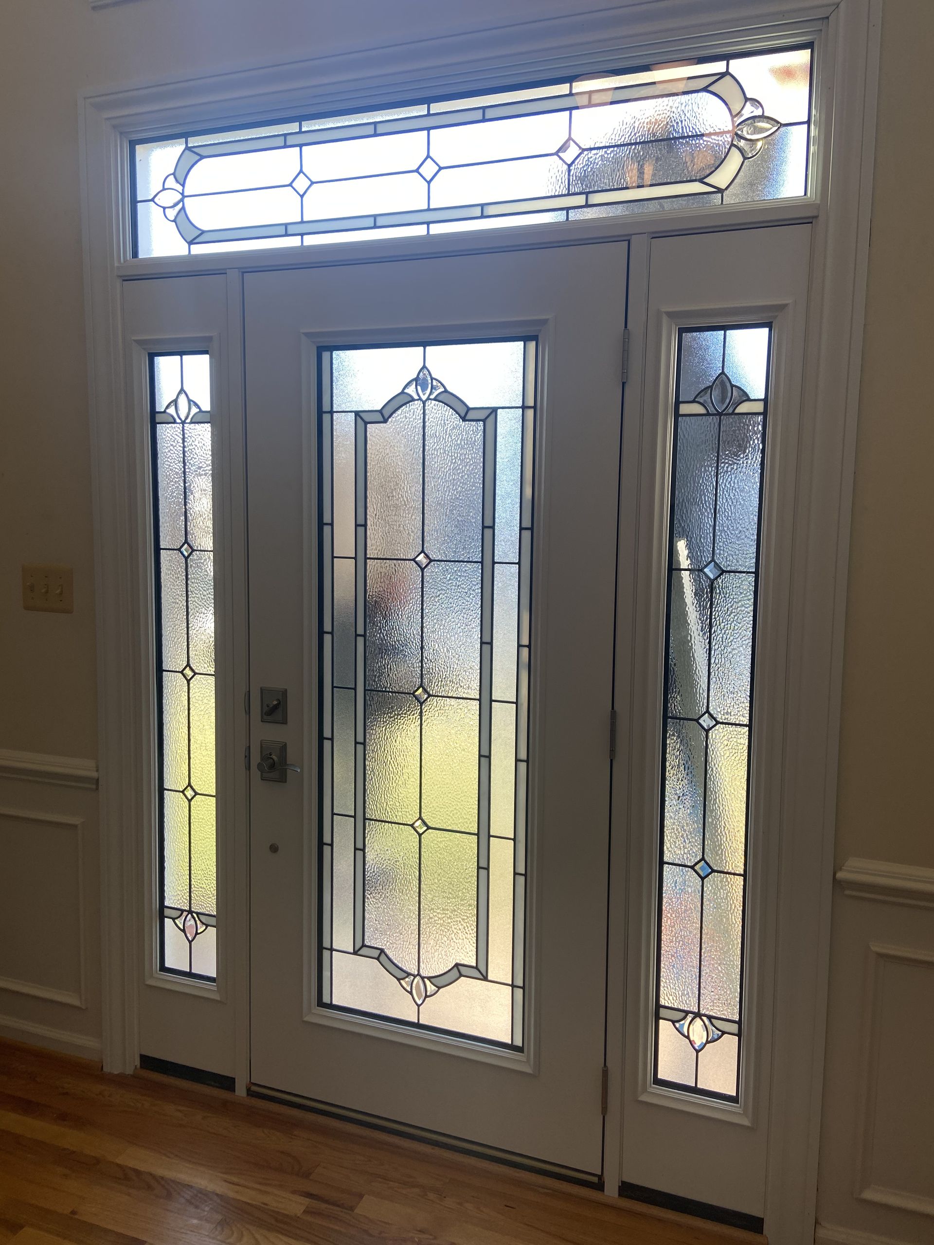 White front door with frosted glass panels and decorative stained glass transom.