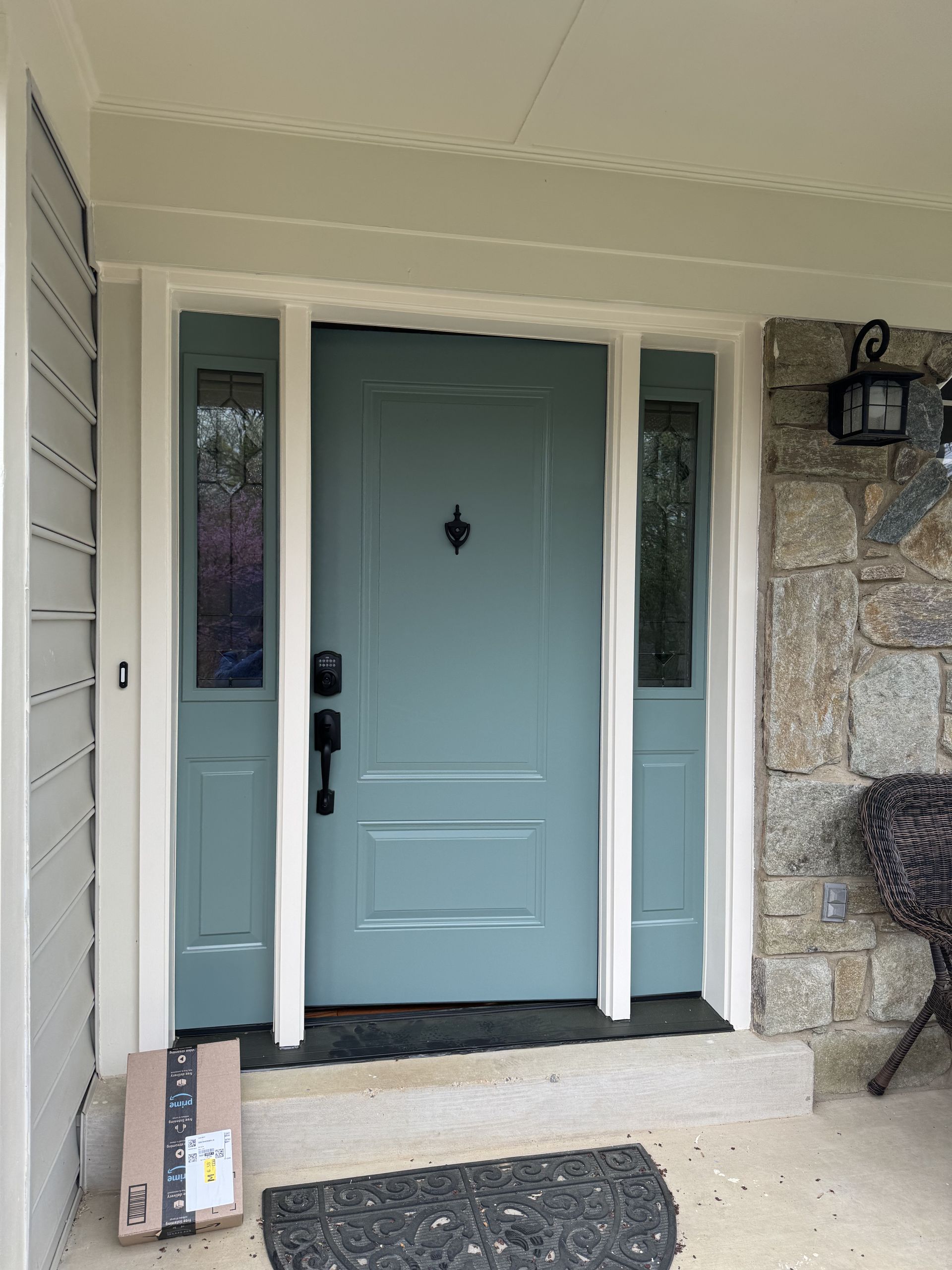 Blue front door with sidelights, white trim, and a package on the step.