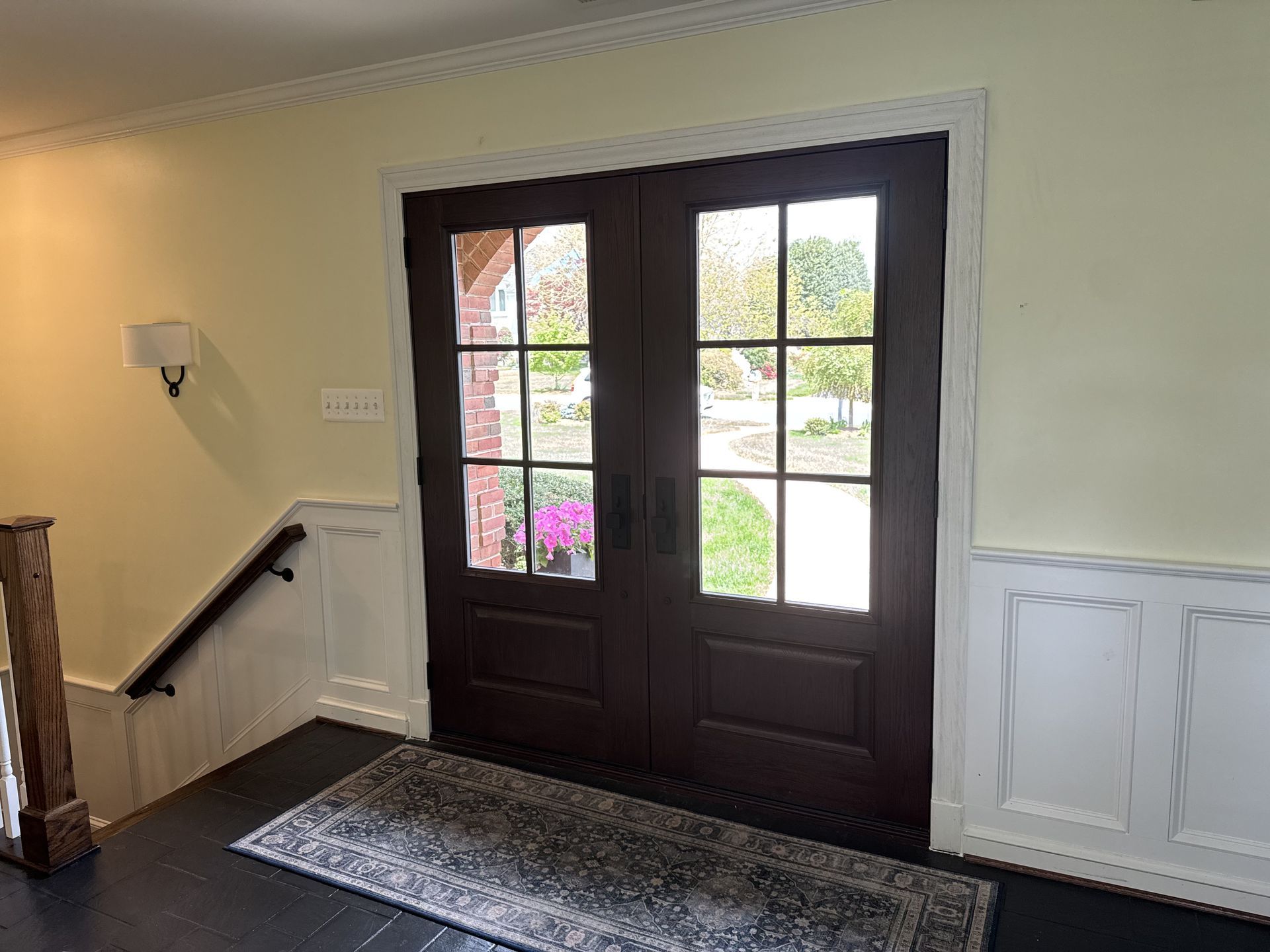 Double brown doors with glass panes, gray rug, cream walls and trim.