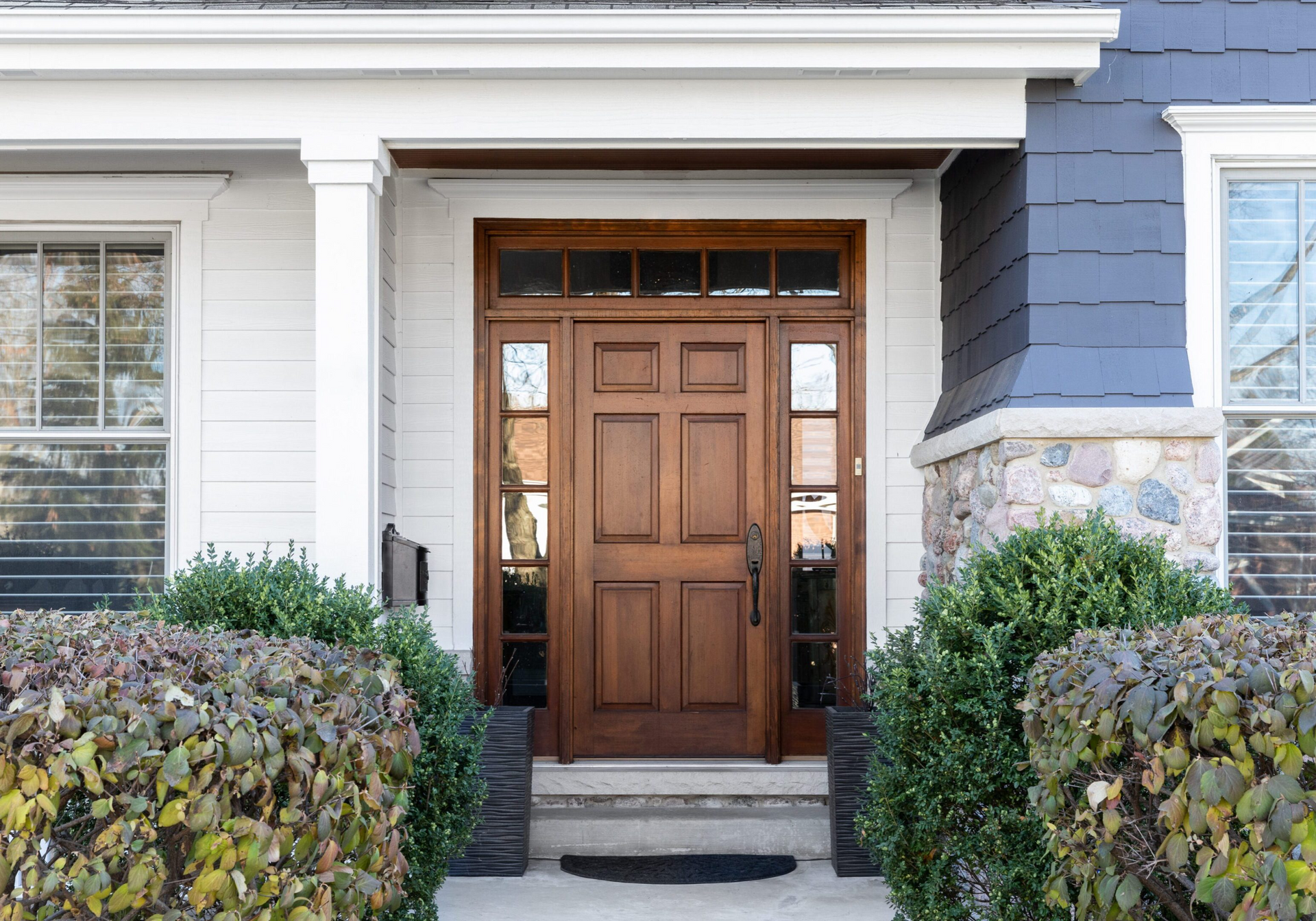 The front door of a house with a wooden door and steps.