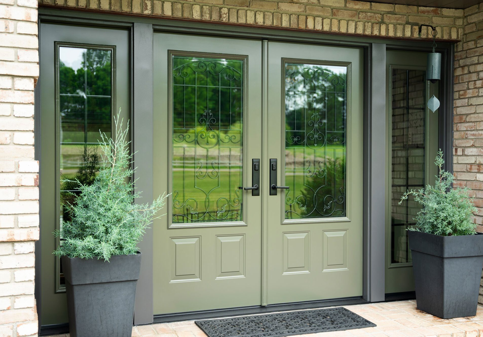 A brick building with a green door and two potted plants in front of it