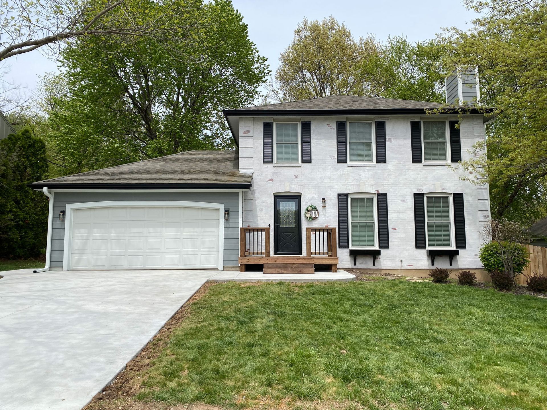 A white house with black shutters and a large garage.