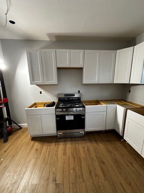 A kitchen with white cabinets, a stove and a sink.