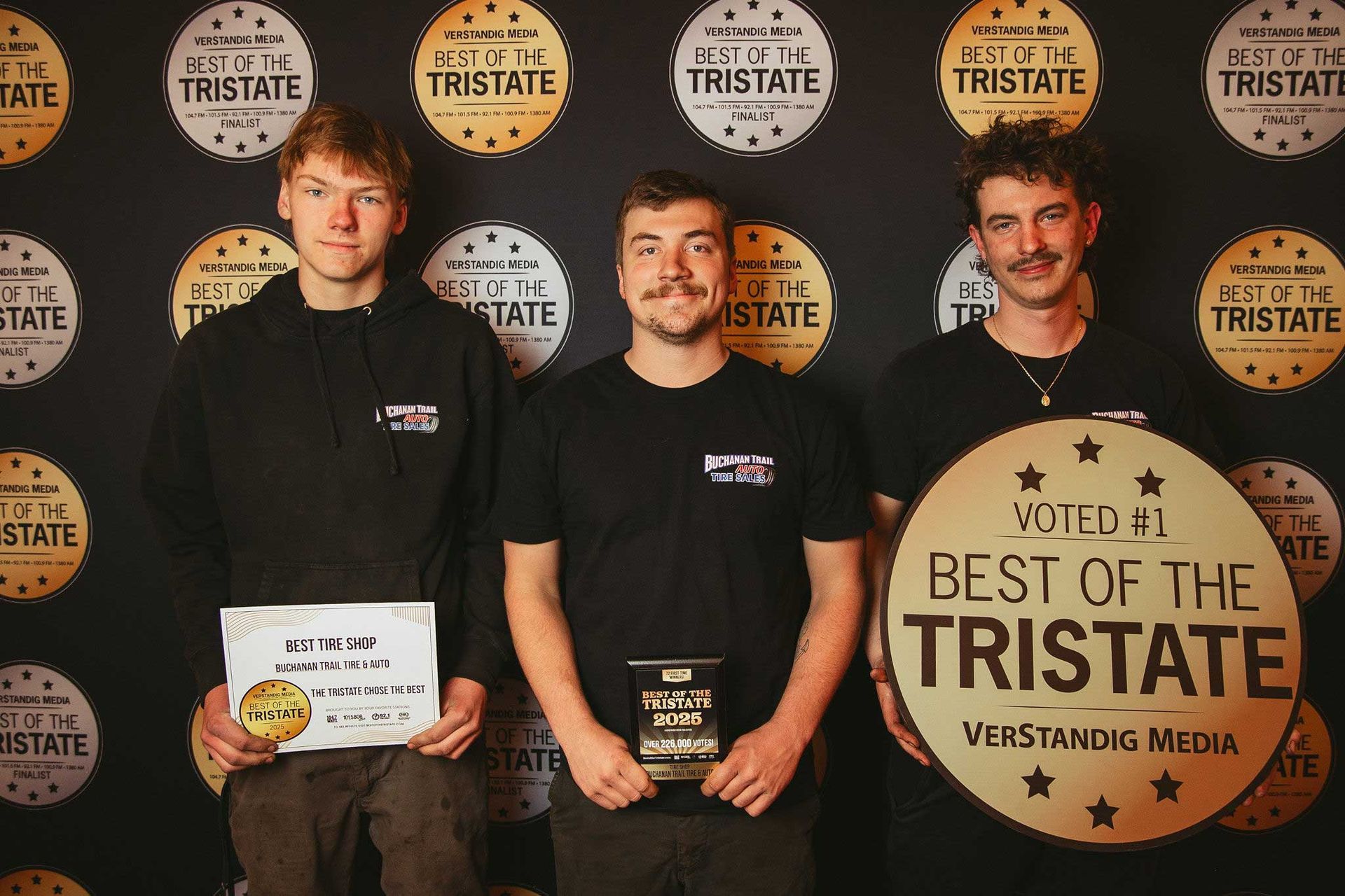 Three people holding awards in front of a backdrop that says 