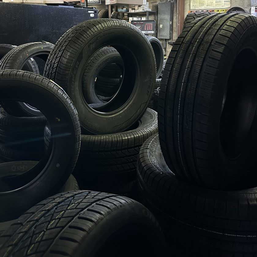 Pile of used black car tires in a garage or storage area.