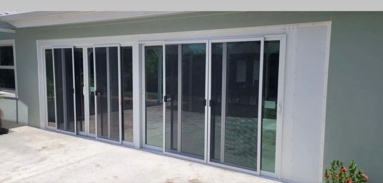 Sliding glass doors with screens on a light green building.
