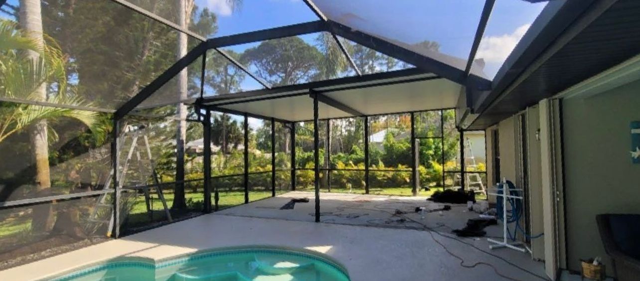 A screened-in porch with a pool, open to a lush green yard on a sunny day.
