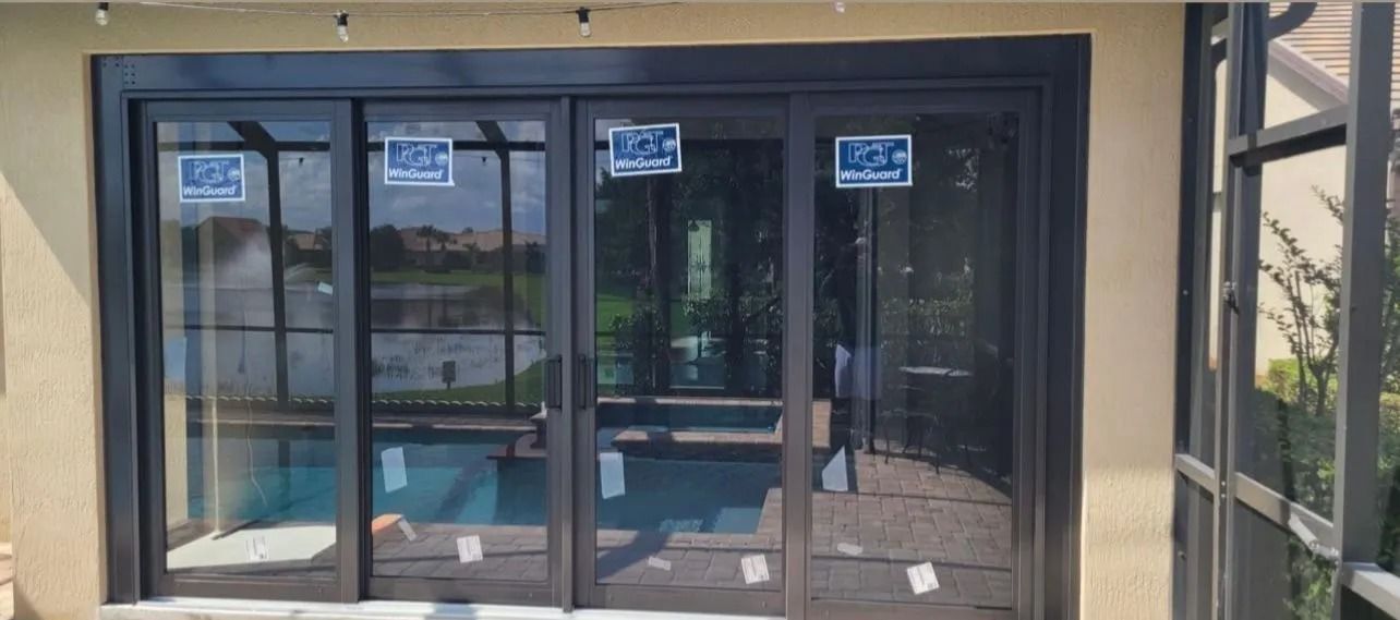 Glass doors with black frames open to a pool; a sunny exterior.