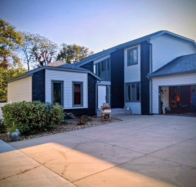 House with white and dark blue siding, concrete driveway, and open garage.