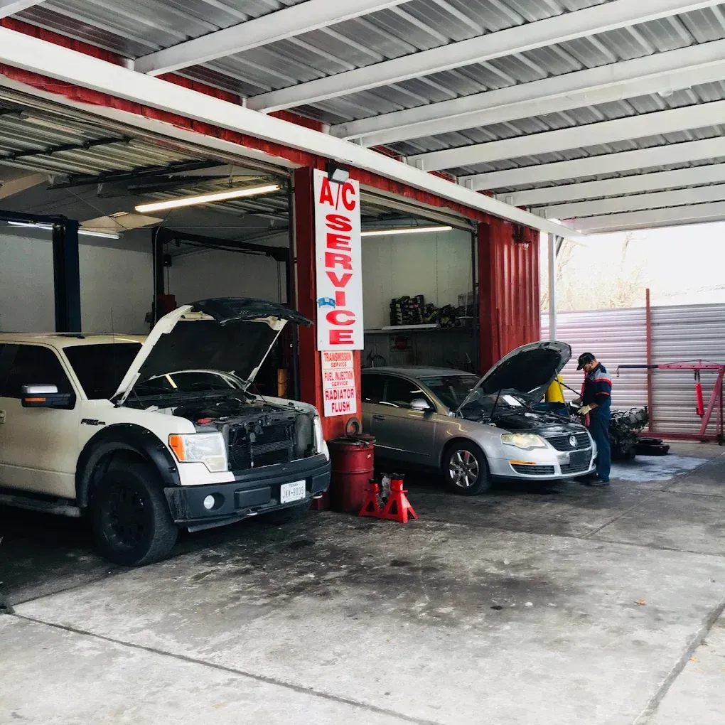 A man is working on a car in a garage with a sign that says ac service.