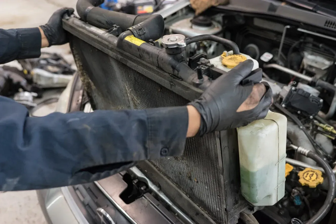 A mechanic is working on the radiator of a car.