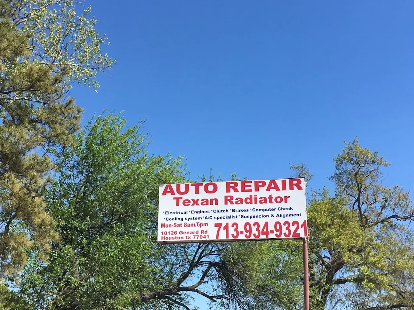 A sign for auto repair texan radiator is hanging from a pole.