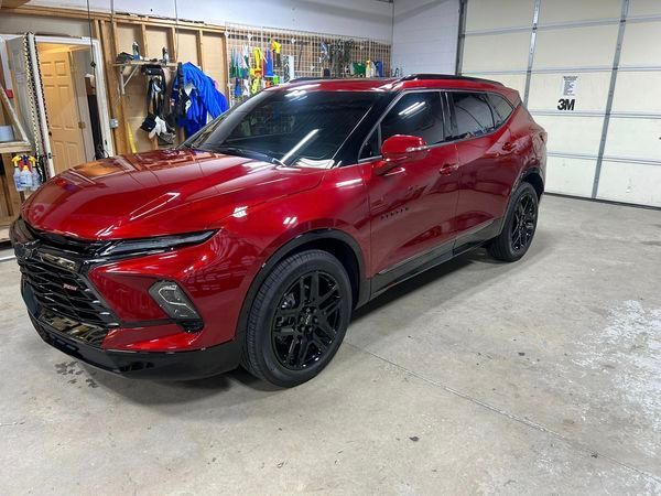 A red car is parked in a garage next to a garage door.