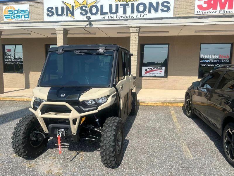 A can am defender is parked in front of a sun solutions building.
