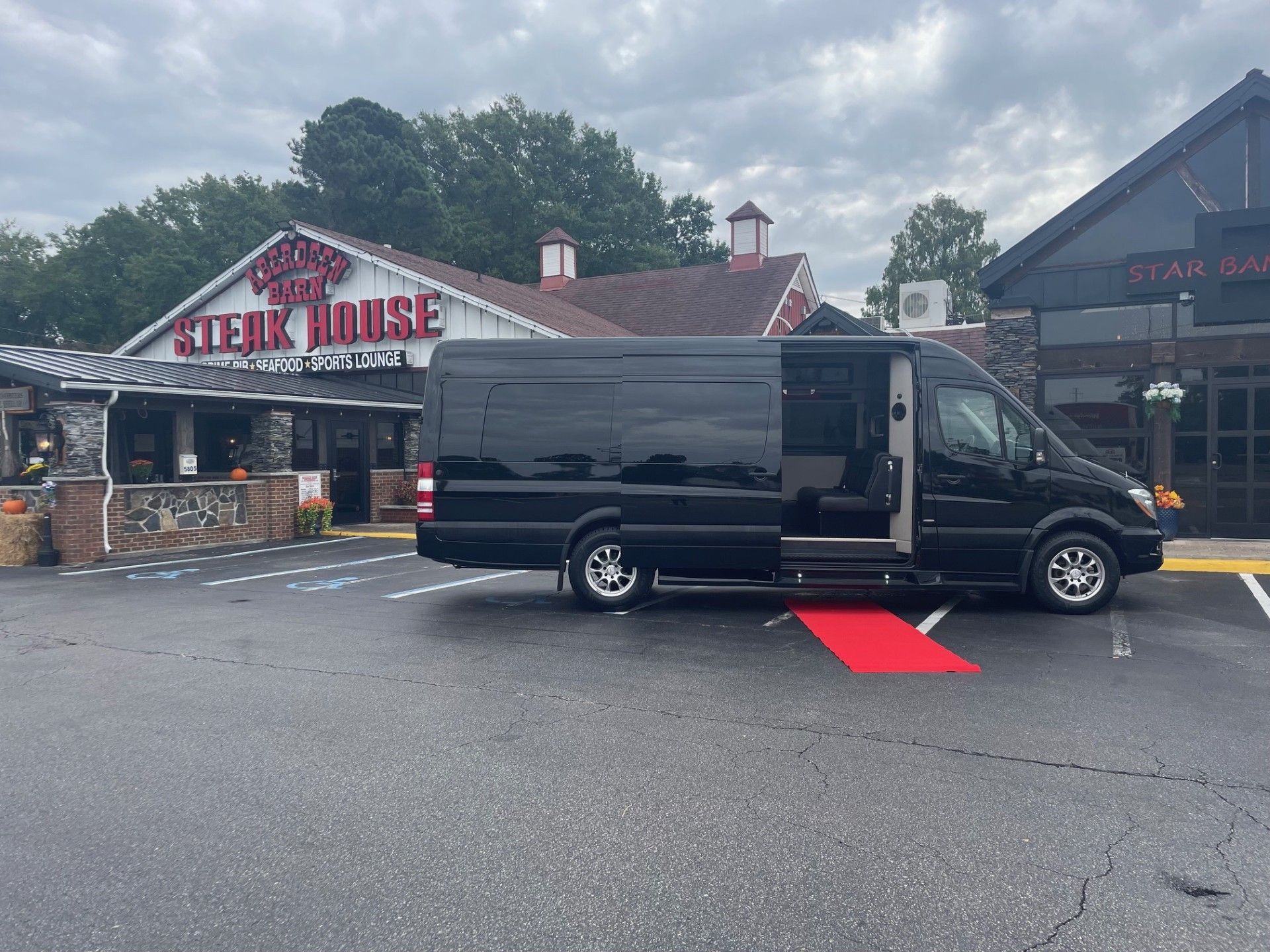 Black van with red ramp deployed at a restaurant entrance. 