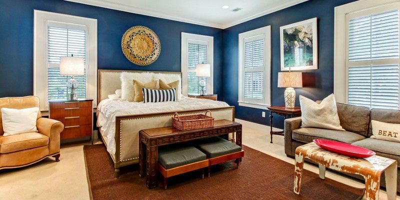 A bedroom with blue walls , a bed , a couch , and a chair.