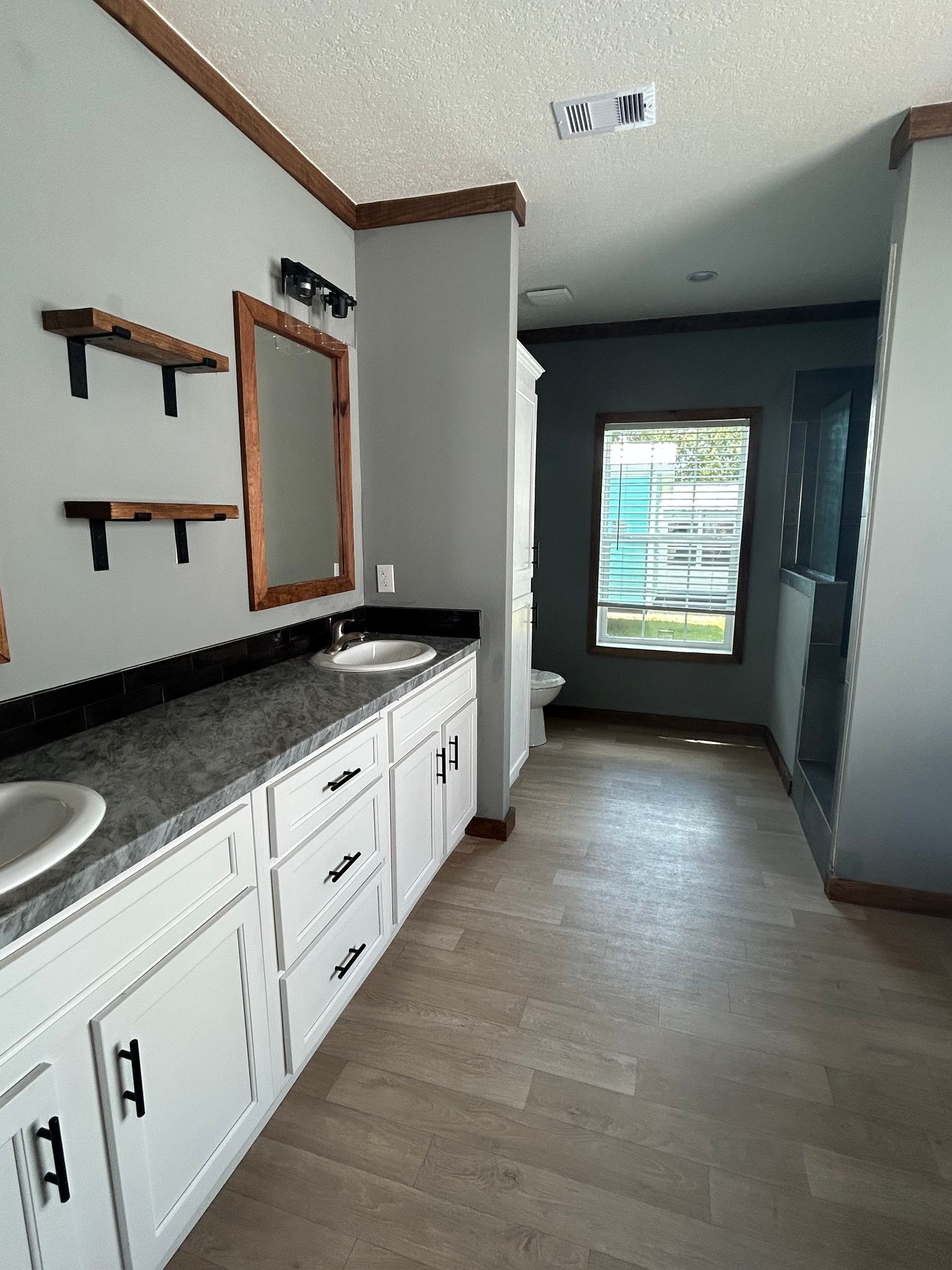 Bathroom with gray walls, white cabinets, and wooden accents.