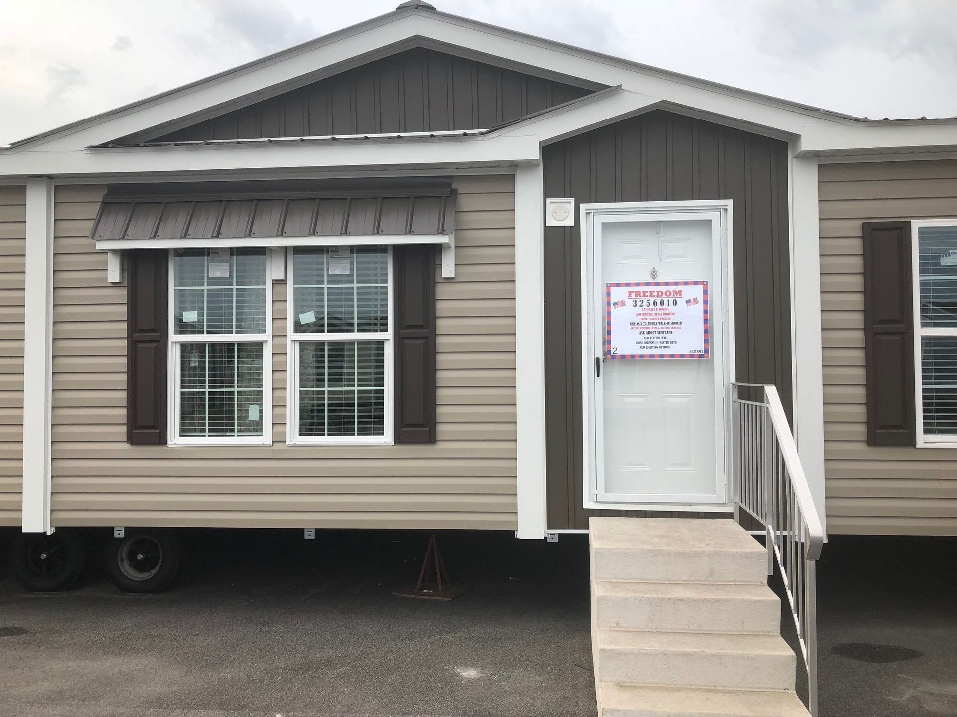 Tan and brown mobile home with white door, steps, and sign.