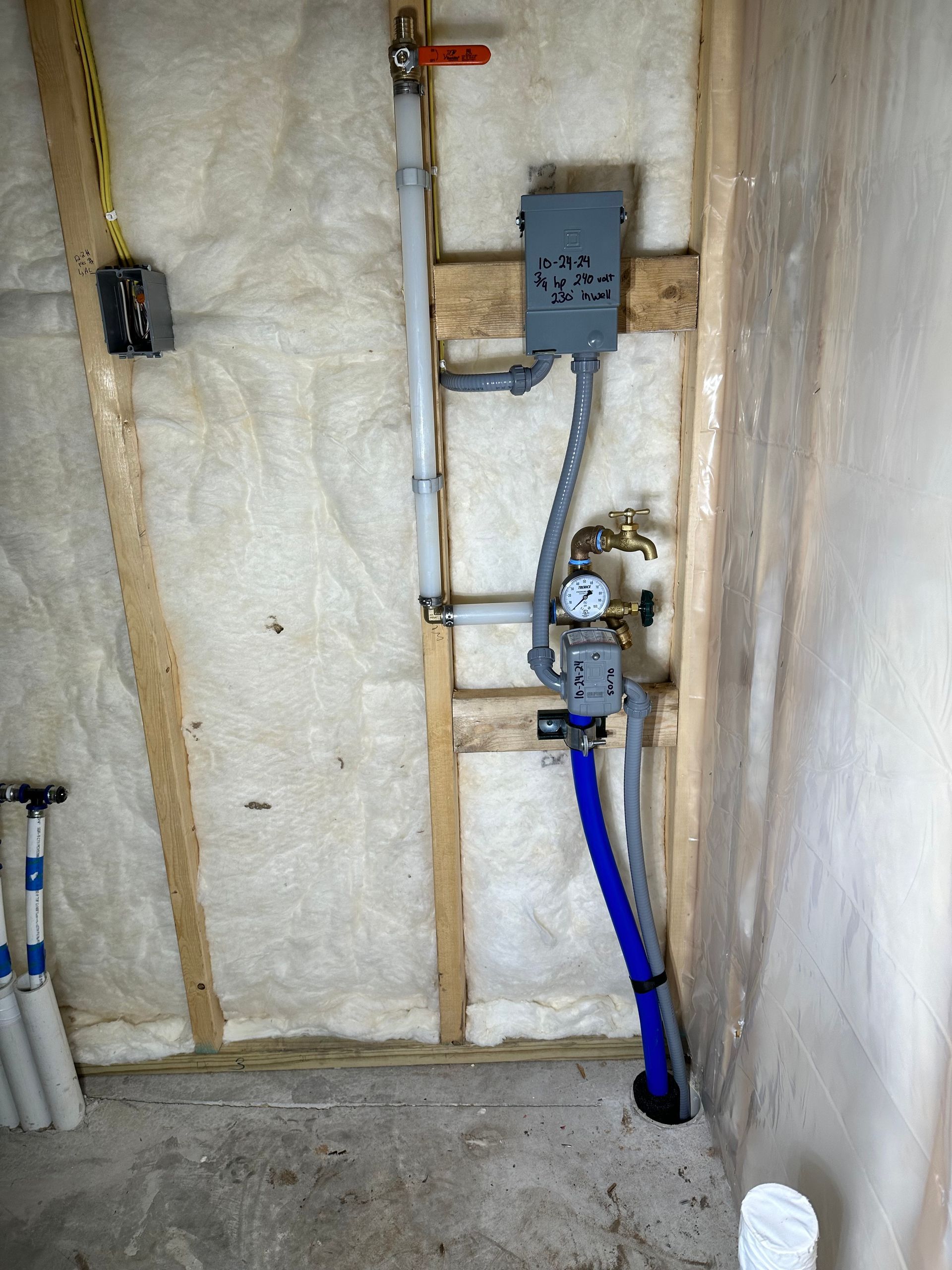 Insulated utility wall with electrical boxes, exposed wiring, and blue conduit in a basement-like space