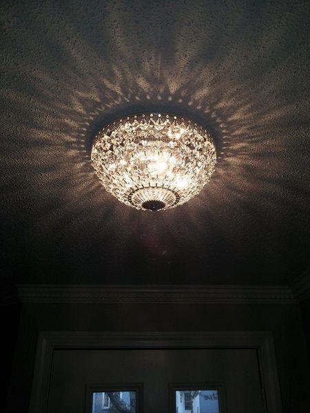 Ornate crystal ceiling light casting patterned light on the ceiling.
