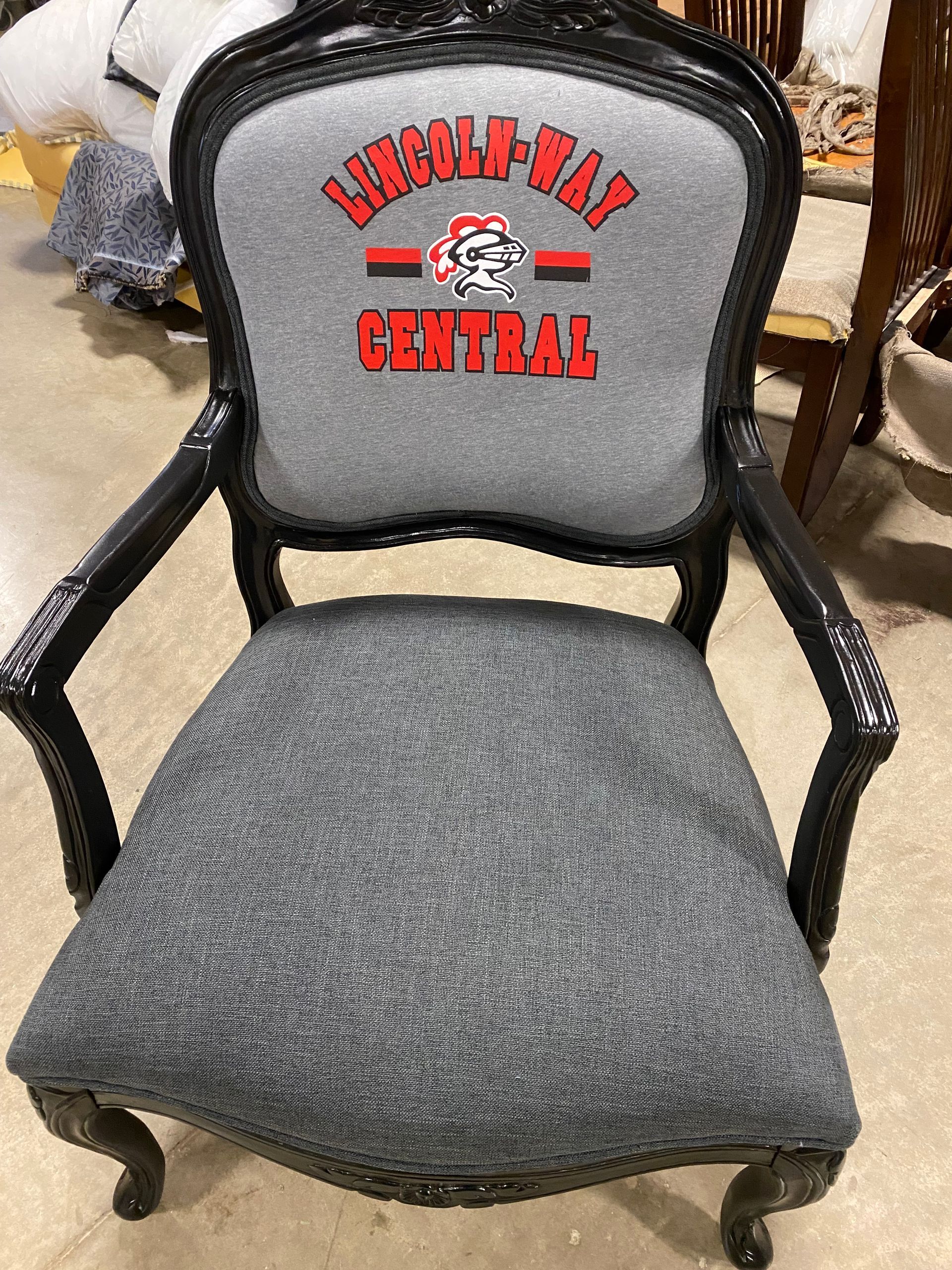 Black armchair with gray fabric seat and back. The back has a Lincoln-Way Central logo in red and white.