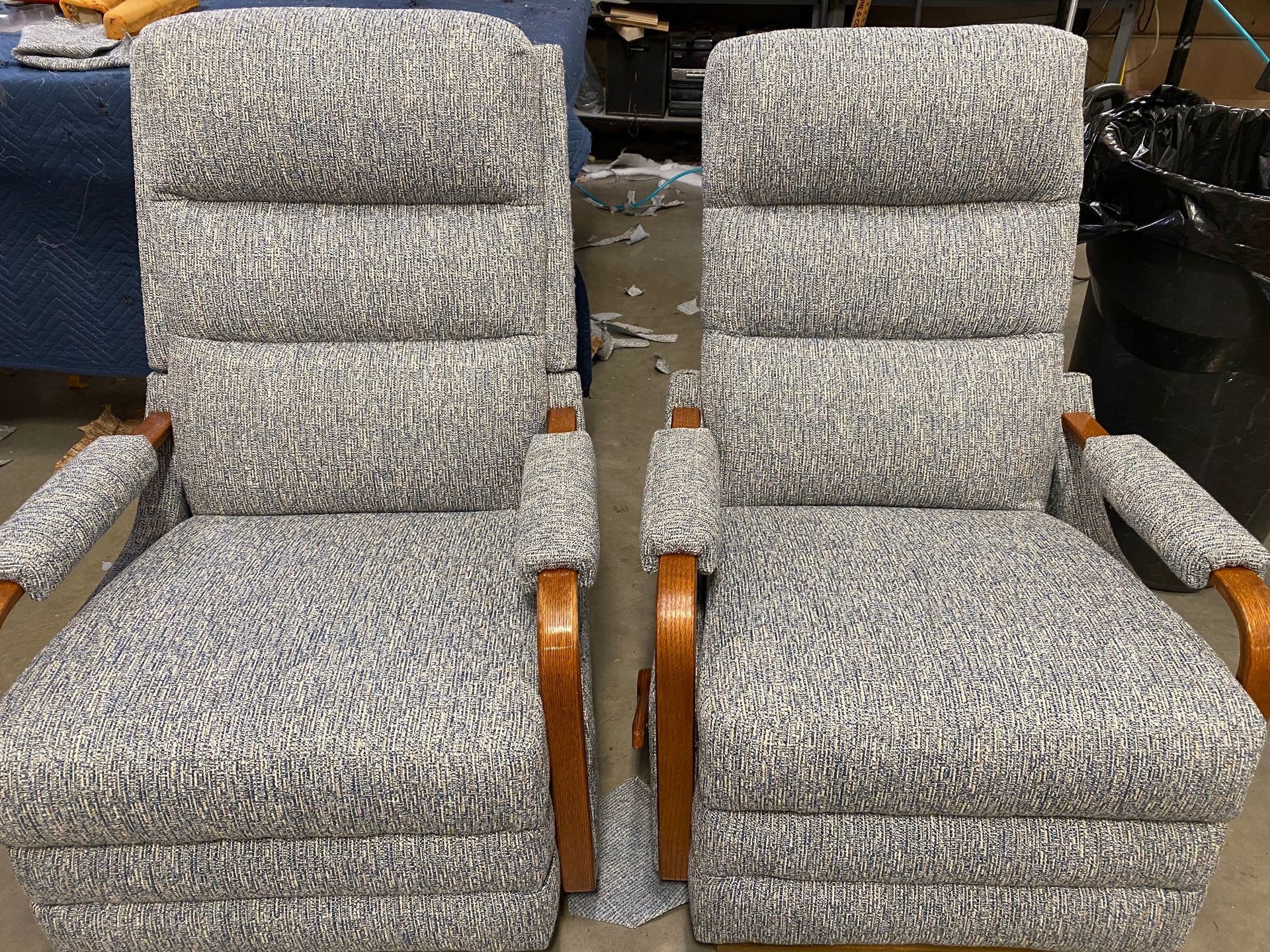 Two upholstered armchairs with a speckled gray and white pattern, wooden arms, and high backs.