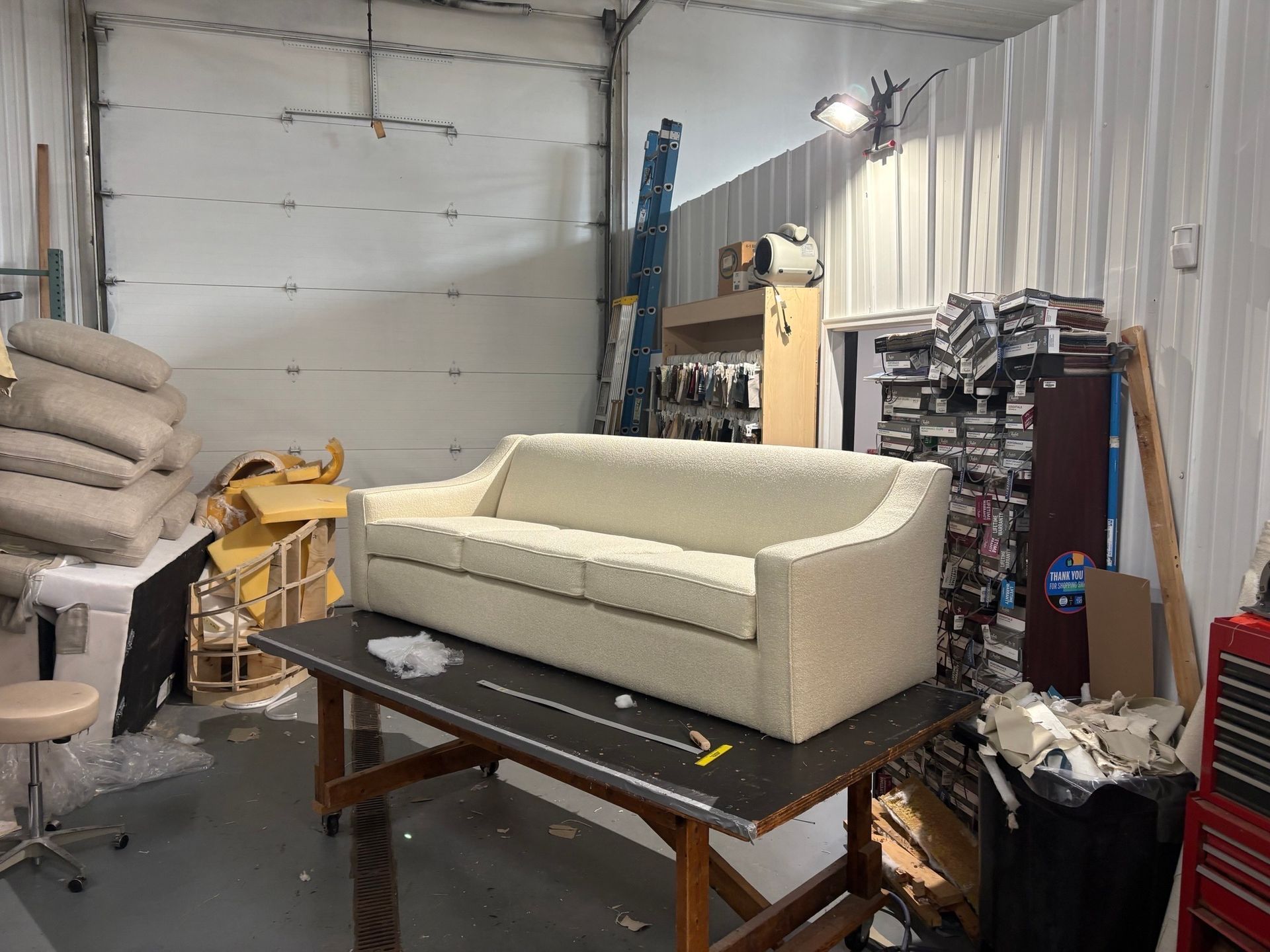 Sofa on a work table in a workshop, surrounded by materials and tools.